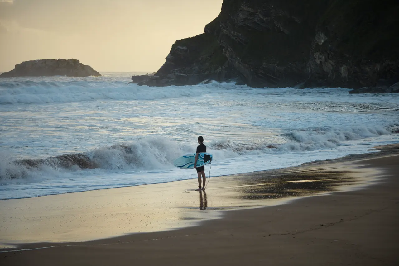 Surfer at sunrise on an empty beach